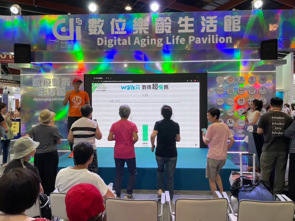 Walkii 數碼超慢跑現場體驗，參與者在數位樂齡生活館跟著引導活動，螢幕顯示任務與運動進度。