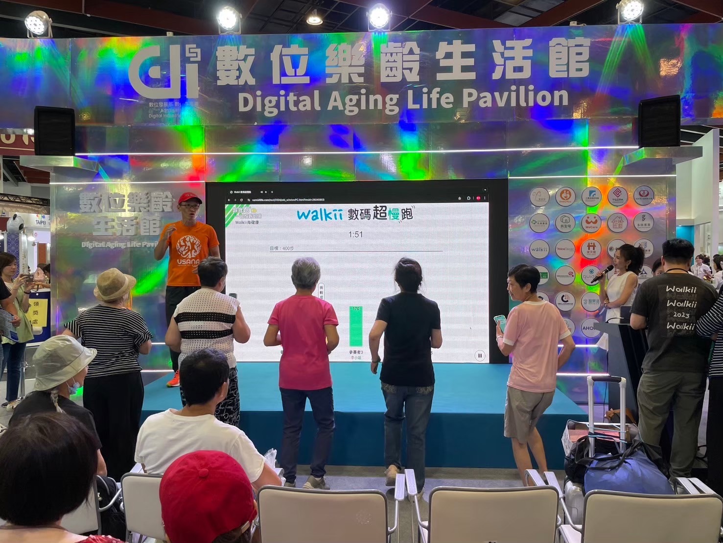 Walkii 數碼超慢跑現場體驗，參與者在數位樂齡生活館跟著引導活動，螢幕顯示任務與運動進度。